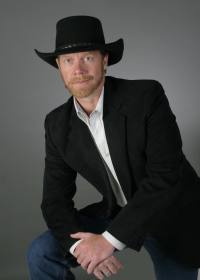 Guy Smith | Gun Facts | standing in black jacket and hat